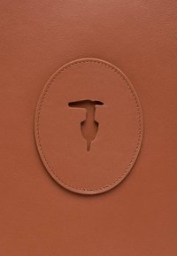 Borsa a tracolla in pelle marrone con un design a taglio circolare, cuciture dettagliate e una texture liscia. Forma compatta e minimalista.