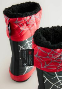 Bottes isolées rouges et noires avec un haut matelassé, motif de toile d'araignée et doublure douce noire, étiquetées comme résistantes à l'eau et imperméables.