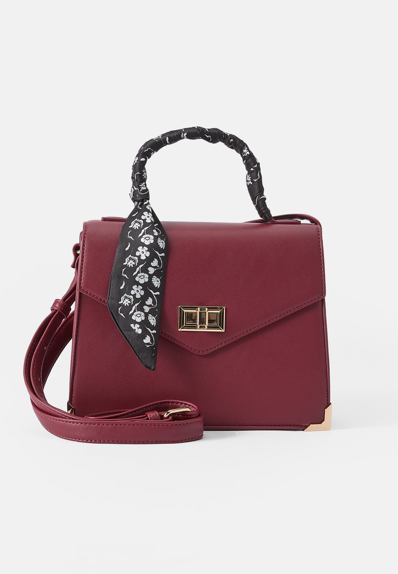 Borsa a tracolla in ecopelle bordeaux con manico a sciarpa nera attorcigliata, accessori in oro e design strutturato; presenta una tracolla staccabile.