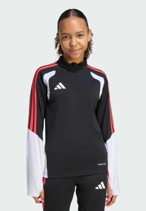 Top atletico nero con accenti rossi e bianchi, maniche lunghe, colletto alto, zip frontale e logo Adidas sul petto sinistro. Tessuto di consistenza liscia.
