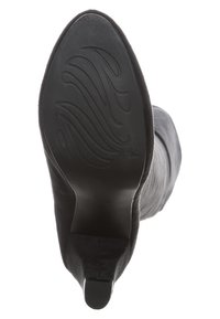 Black boot with a smooth suede exterior, pointed toe, and a textured rubber sole featuring wave patterns for grip and stability.