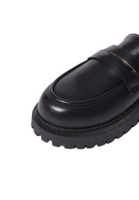 Mocassino in pelle nera con punta arrotondata, dotato di una fascia prominente sulla parte frontale e suola in gomma rigida per una buona aderenza.