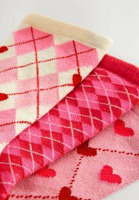 Drei Paar rosa Socken mit verschiedenen Mustern: Argyle mit Herzen, einfarbig rosa und Herzmotiven, alle aus weichem, strukturierter Stoff.