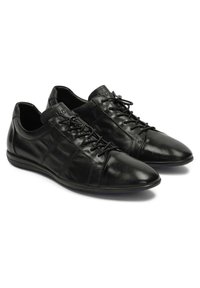 Pantofi negri din piele cu textură netedă, vârf rotunjit și design cu șireturi. Prezintă cusături subtile și o talpă subțire din cauciuc.