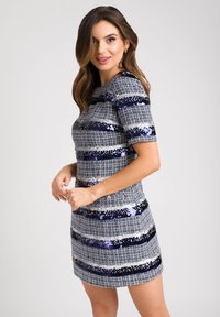 Sukienka z krótkim rękawem z teksturowanej niebieskiej tkaniny z paskami z cekinów. Posiada dopasowaną sylwetkę z okrągłym dekoltem.