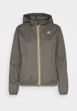 Veste légère kaki avec capuche, dotée d'une fermeture éclair à l'avant avec des rayures blanches, bleues et jaunes, et d'un patch logo sur la poitrine.