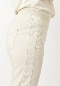 Beige Hose mit glatter Textur, hoch sitzendem Bund, seitlichen Nahtdetails und einer Rücktaschengestaltung.