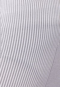 Tessuto a righe con sottili linee grigie su sfondo bianco, caratterizzato da una combinazione di superfici lisce e texture.