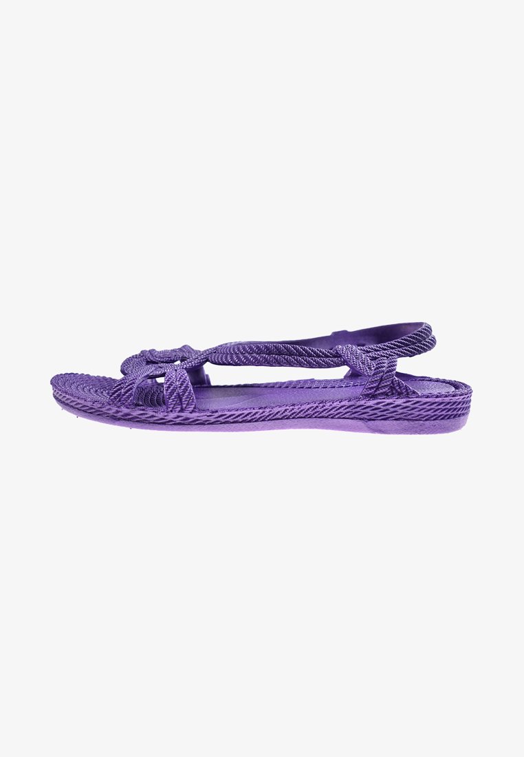 Sandalias moradas con un diseño trenzado y correas ajustables. Suela plana con un acabado texturizado, que ofrece un ajuste flexible y seguro.