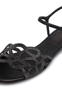 Schwarze Sandale mit einem Riemchen-Design, versehen mit einem dekorativen Muster aus schwarzen Perlen im oberen Bereich. Glatte Sohle mit dezentem Branding.