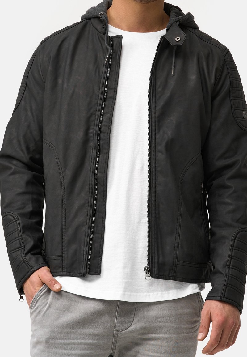 Musta nahkainen pommittajatakki, jossa on harmaa huppu, vetoketjukiinnitys, teksturoitu olkatyöstö ja sivutaskut.