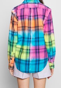Värikkään ruudullinen paita, jossa on kirkkaita sävyjä vaaleanpunaisesta, oranssista, sinisestä ja vihreästä. Valmistettu kevyestä kankaasta, jossa on pitkät hihat ja nappirannekkeet.
