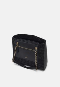 Svart tote-väska med texturerad tyg och släta läderdetaljer. Har en framficka med dragkedja och guldtonade kedjehandtag.