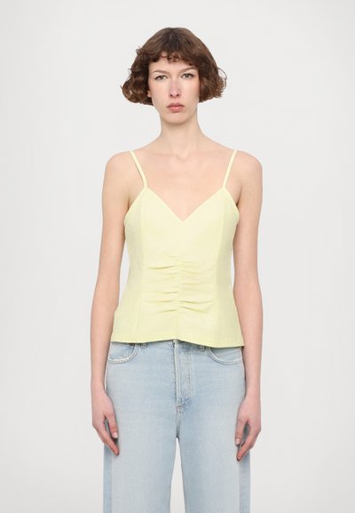 Camisola gialla chiaro con spalline sottili, caratterizzata da una scollatura a V e arricciature sul davanti. Il tessuto ha una texture liscia e una silhouette aderente.