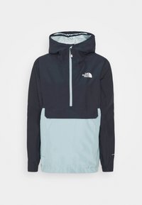Anorak à capuche bicolore noir et bleu clair avec une fermeture éclair frontale partielle et le logo The North Face sur la poitrine.