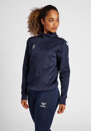 Granatowa sportowa rozpinana bluza z długimi rękawami, gładki materiał, logo na piersi oraz kontrastowe pasy na ramionach. W zestawie z dopasowanymi legginsami.