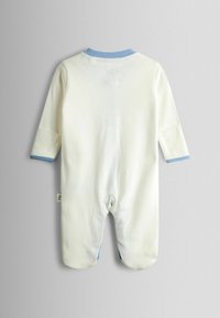 Hvid babyheldragt med lange ærmer og blå kant på krave og manchetter, med indbyggede fødder, lagt fladt med bagsiden opad på en grå overflade.