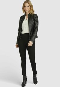 Black leather biker jacket with a stand-up collar, zipped front, paired with fitted black pants and high-heeled black ankle boots.