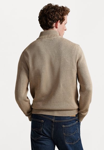 Beige strikket sweater med høj krave, ribbede manchetter og nederste kant. Tekstureret stof, tætsiddende design og vist fra ryggen.
