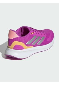 Baskets de sport roses avec un dessus en maille respirante, accents jaunes et argentés, et une semelle blanche texturée pour une meilleure adhérence.