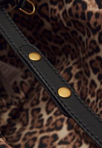 Cinturino in pelle nera con borchie dorate, con un interno in stampa leopardata dai toni marroni e beige.