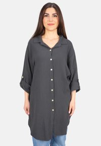 Loose-fitting, dark gray shirt made of textured fabric with a collar, button-down front, and rolled-up sleeves. Features small buttons.