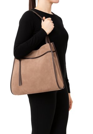 Sac fourre-tout en suède brun avec des finitions en cuir marron foncé, présentant une texture douce, de longues poignées et une frange décorative à l'avant.