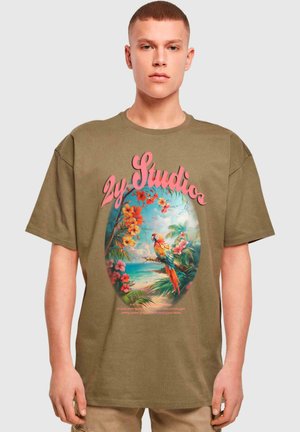 Olivově zelené oversized tričko s živou grafikou tropických květin a papouška, secházející se růžovým textem a kulatým motivem ve středu.