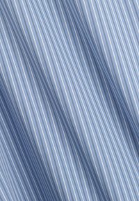 Tissu bleu clair avec de fines rayures verticales blanches et bleu foncé, présenté avec des plis et des ombres naturels.