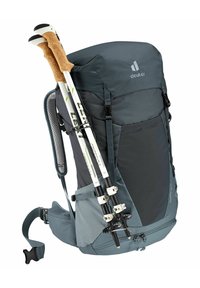 Deuter Wander-Rucksack in Dunkelgrau mit schwarzen Akzenten. Verfügt über ergonomische Tragegurte, eine obere Klappe, Mesh-Polsterung und Seitentaschen. Enthält Trekkingstöcke.