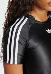 Svart atletisk tröja med korta ärmar, blank yta, vit tre-stripes design längs axlarna och en liten vit logotyp på bröstet.