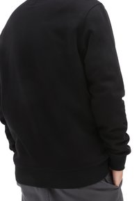 Felpa nera con maniche lunghe, polsini e vita a coste. Texture liscia con un leggero lucido, presenta un colletto rotondo e un design minimalista.