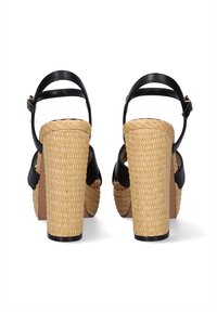 Sandalias de tacón alto de cuero negro con plataforma de paja trenzada gruesa y tacón cuadrado. Correa del tobillo ajustable y diseño de punta abierta.