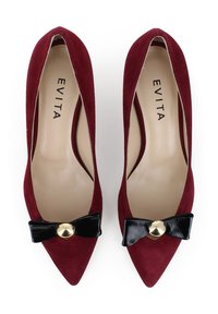Tacchi a punta in suede bordeaux con un fiocco in pelle verniciata nera e un accento dorato al centro. Interno beige.