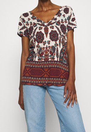 Short-sleeve V-neck top in cream with intricate floral and paisley patterns in red and teal, featuring a textured lower band design.