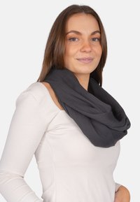 Black infinity scarf made of soft fabric, featuring a textured finish and layered design, worn around the neck.