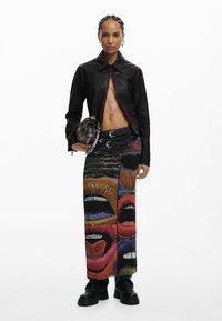 Mustast nahast lühike jakk esikinnisega, kombineeritud värvika, graafilise mustriga maxi seelikuga, kus on julged huulekujundid. Mustad massiivsed saapad.