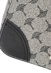 Textured fabric in black and white with a pattern of fan shapes, featuring a black leather accented corner with white stitching.