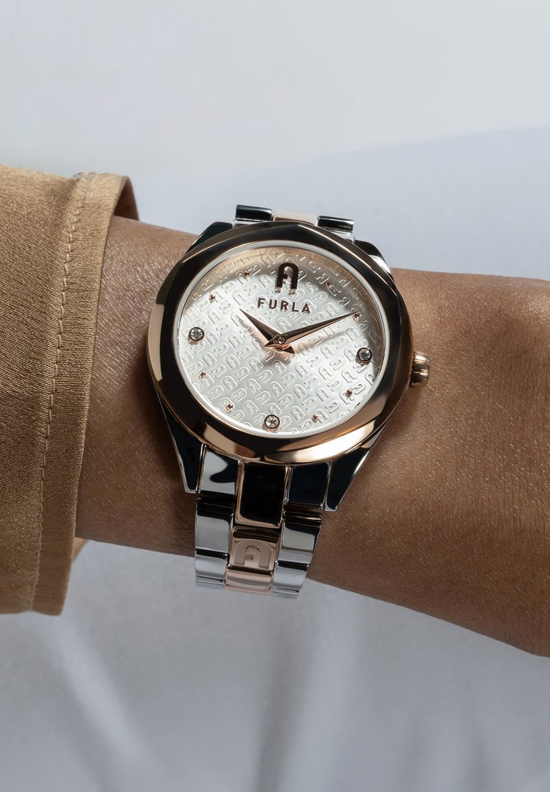 Furla-klocka med ett runt hus i silver och roséguld, mönstrad silverklocka, notcherade index och länkad metallarmband.