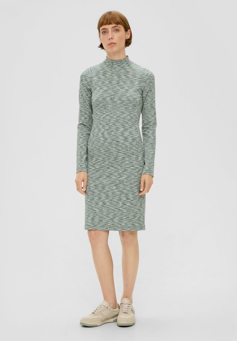 Sweterkowa sukienka z długim rękawem w jasnoróżowym wzorze. Posiada wysoką szyję, dopasowany krój i kończy się tuż nad kolanem.