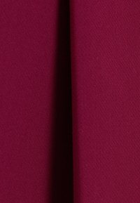 Bordeaux stof met een gladde textuur, met een subtiele stretch. De afbeelding toont twee draperieën die samen gevouwen zijn, waardoor zachte schaduwen ontstaan.