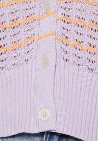 Cardigan tricoté lavande avec un motif ajouré, des rayures orange et un ourlet côtelé. Comprend des boutons clairs avec un design simple à quatre trous.