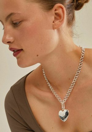 Sølv kædedyse med et poleret hjertependant, med et chunky link-design og reflekterende tekstur.