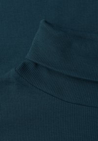 Petrolblauwe geribbelde stof met een hoge hals. De textuur is rekbaar en heeft verticale strepen. De kraag is omgevouwen, wat diepte aan het ontwerp geeft.