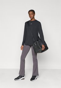 Must musta varrukatega must särk väikese valge logoga, lilla laienevate pükste, mustade tossude ja musta võrkkotiga. 