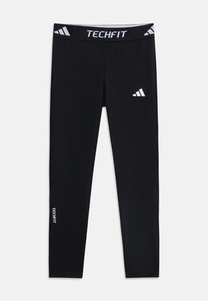 Leggings de compression sportifs noirs avec ceinture « TECHFIT », logo Adidas sur la cuisse et texte « TECHFIT » sur le bas de la jambe.