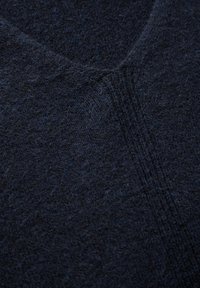 Donkerblauw gebreid sweaterstof met een zachte textuur, v-hals ontwerp en subtiele stikdetails. Dichte weving zonder zichtbare patronen.