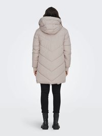 Beżowa, ocieplana parka w wzór chevron, z kapturem i zapięciem na napy. Nosi się ją na czarne rurki i czarne buty. Gładka tekstura.