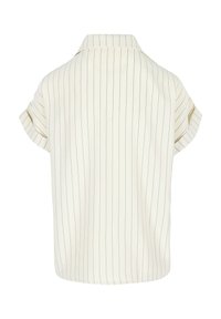 Elevandiluuvalge lühikeste varrukatega pluus õhukeste vertikaalsete mustade triipudega ja väikese püsti kaelusega, nähtud tagantpoolt.