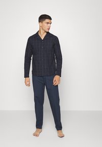 Conjunto de pijama de cuadros en azul marino para hombre. Camisa de manga larga con botones y cuello, y pantalones a juego, ambos confeccionados en una tela suave.